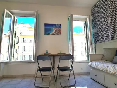 a room with two chairs and a table in front of two windows at NICE - Studio cosy hypercentre à 500m de la plage in Nice
