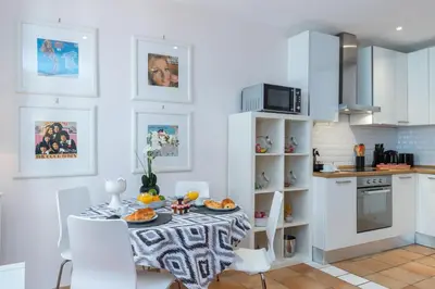 a white kitchen with a table and chairs in a room at 8 CONDAMINE - Stylish in Old Town - 2 pièces - 300m de la mer in Nice