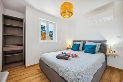a bedroom with a large bed with blue pillows at Cosy & Chill Appartements - 10 min de la mer - Jardin, Netflix, terrasse, fibre & parking in Cagnes-sur-Mer