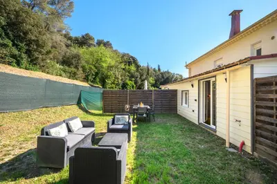 a backyard with couches and a table and a fence at Cosy & Chill Appartements - 10 min de la mer - Jardin, Netflix, terrasse, fibre & parking in Cagnes-sur-Mer