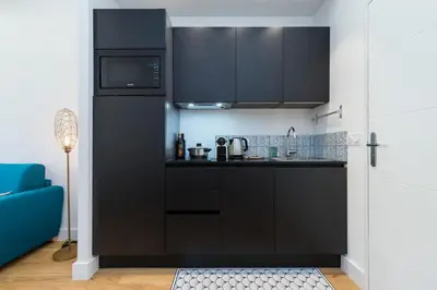 a kitchen with black cabinets and a microwave at Cosy 1 Bdr Place Garibaldi & Place du Pin in Nice