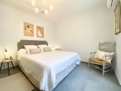 a bedroom with a large white bed and a chair at Cozy 2BR Appartment near the Port of Nice in Nice