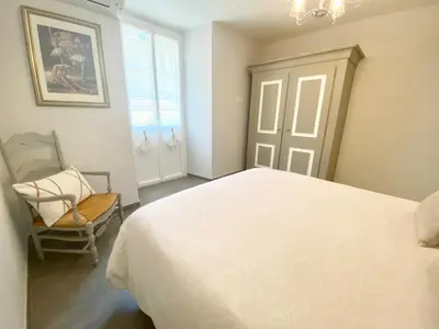 a bedroom with a large white bed and a chair at Cozy 2BR Appartment near the Port of Nice in Nice