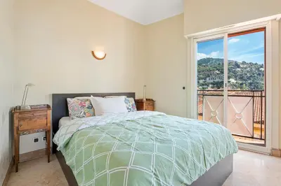 a bedroom with a bed and a large window at Penthouse La Bellevue in Villefranche-sur-Mer