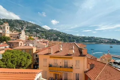 a view of a town with buildings and the water at Penthouse La Bellevue in Villefranche-sur-Mer