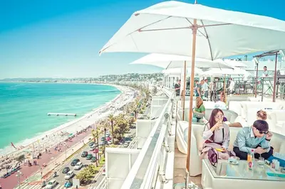 a group of people sitting on a bar overlooking the beach at Bienvenue sur la Cote d'Azur in Nice