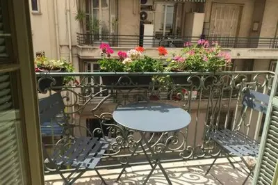 a table and chairs on a balcony with flowers at Le GIULIANO in Nice