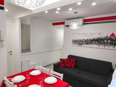a living room with a red table and a black couch at Logement de Catherine in Nice