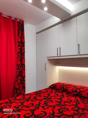 a bedroom with a red bed and white cabinets at Logement de Catherine in Nice
