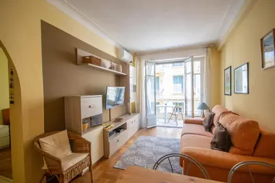 a living room with a couch and a tv at Joli 2 pièces climatisé à 150m de la plage in Nice
