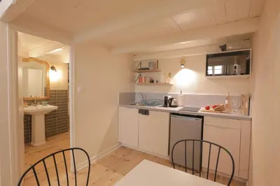 a kitchen with white cabinets and a sink and chairs at Charmant Studio climatisé - Vieux Nice in Nice