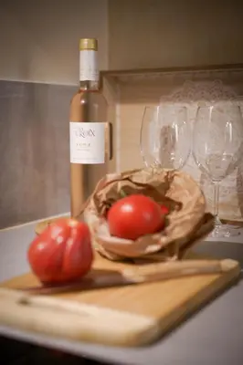 a bottle of wine and two tomatoes on a cutting board at Charmant Studio climatisé - Vieux Nice in Nice