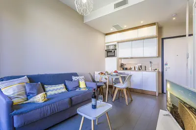 a living room with a blue couch and a kitchen at MY CASA - GAMBETTA 33 - 5min walk to beach in Nice