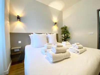 a pile of towels sitting on top of a bed at Maxim - Easy Home Booking in Nice