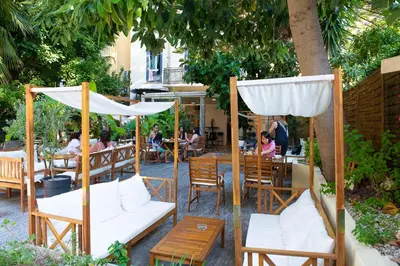 a patio with white umbrellas and people sitting at tables at Auberge de Jeunesse HI Nice Les Camélias in Nice