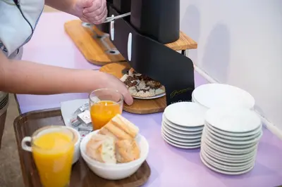 a person preparing a breakfast of toast and orange juice at Auberge de Jeunesse HI Nice Les Camélias in Nice