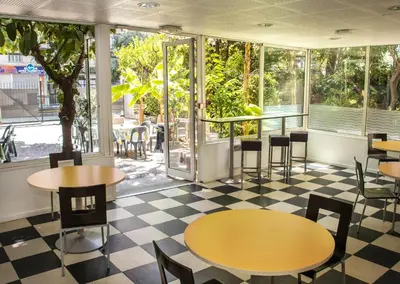 a restaurant with tables and chairs and windows at Auberge de Jeunesse HI Nice Les Camélias in Nice