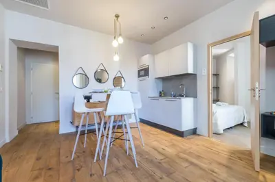 a kitchen and living room with a table and stools at Refined & Cozy 1 Bedroom Downtown in Nice