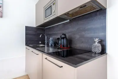 a kitchen with white cabinets and a black counter top at LAMARTINE- Heart of Center- Modern and Design flat in Nice