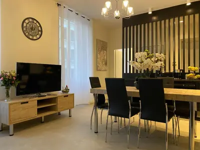 a dining room with a table and chairs and a television at ZEN and Charming - Center -5 min walk to Sea- 2BR in Nice