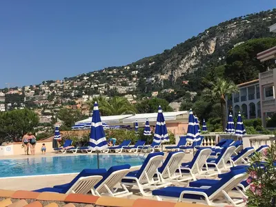 a group of chairs and umbrellas next to a swimming pool at Appartement Ange Gardien Vue Mer in Villefranche-sur-Mer
