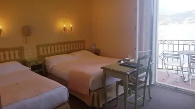 a hotel room with two beds and a table and a balcony at Hôtel de Charme Brise Marine in Saint-Jean-Cap-Ferrat
