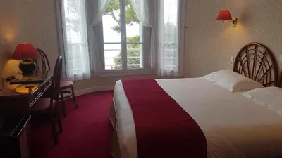 a hotel room with a bed and a desk and windows at Hôtel de Charme Brise Marine in Saint-Jean-Cap-Ferrat