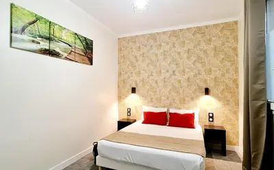 a bedroom with a bed with two red pillows at Evelia Hotels in Nice