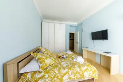 a bedroom with a bed with a yellow blanket and a tv at Wonderful Apartment on Sea in Nice