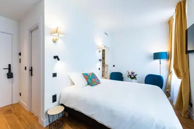 a bedroom with a white bed and blue chairs at Boutique Hotel Nice Côte d'azur in Nice