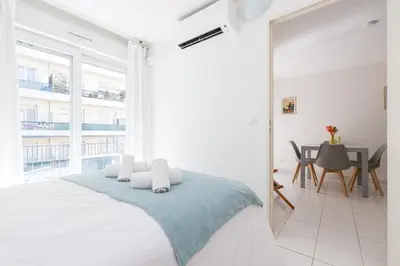 a white bedroom with a bed and a table at Comfortable 1 Bdr Downtown - AC & Parking in Nice