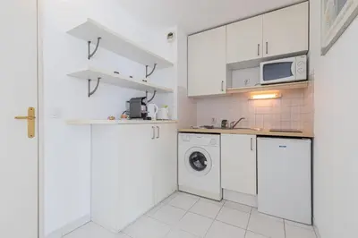 a kitchen with white cabinets and a washer and dryer at Comfortable 1 Bdr Downtown - AC & Parking in Nice
