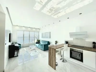 a white living room with a kitchen and a couch at Sea view - Promenade des Anglais in Nice