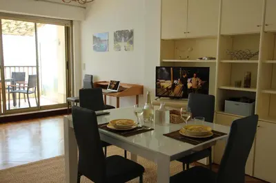 a dining room with a table with chairs and a television at Appartement Front de Mer - Promenade des Anglais in Nice