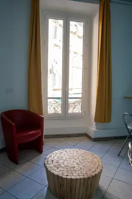 a room with a chair and a table and a window at Le Pastoral in Nice
