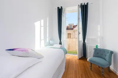 a bedroom with a white bed and a blue chair at MY CASA - GIOFFREDO 14 - Spacious apartment with balcony in Nice