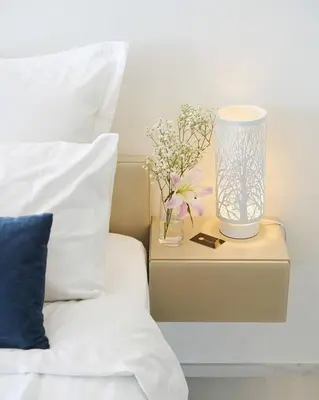 a bedside table with a lamp and flowers on it at Sunlight Properties - Sky blue - 3 bedroom flat with sea view on the Promenade des Anglais in Nice