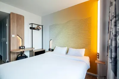 a bedroom with a white bed and a yellow wall at B&B HOTEL Nice Aéroport Arenas in Nice