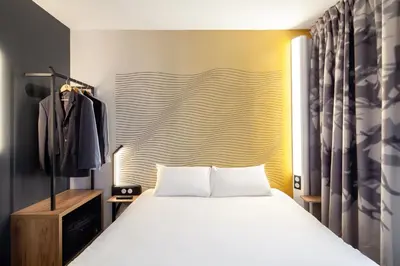 a bedroom with a white bed and a yellow wall at B&B HOTEL Nice Aéroport Arenas in Nice