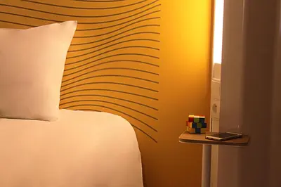 a bedroom with a bed with a pillow and a striped wall at B&B HOTEL Nice Aéroport Arenas in Nice