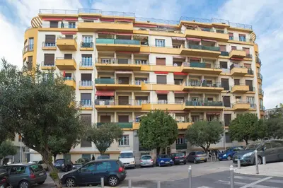 a tall yellow building with cars parked in a parking lot at 26 nice , La Riviera in Nice