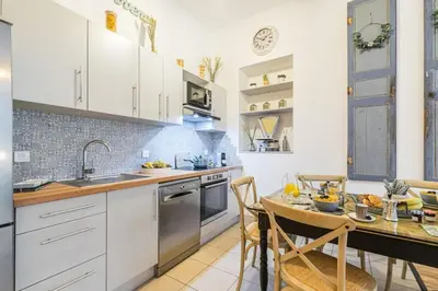 a kitchen with white cabinets and a table and chairs at MY CASA - GALLIENI - Superb & Unique in City Center in Nice