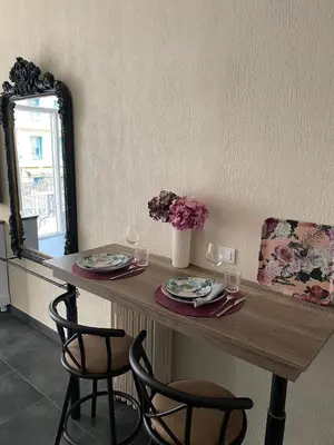 a table with two chairs and two glasses and a mirror at Cozy studio with a sea view in Nice