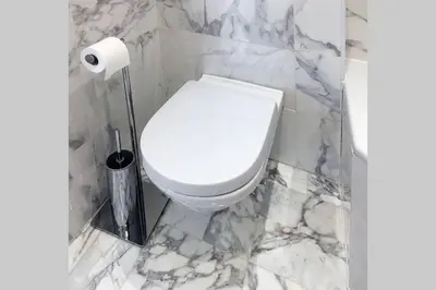 a white toilet in a bathroom with marble walls at Promenade des anglais Amazing sea view 140M2 3BR in Nice