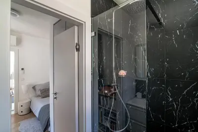 a bathroom with a shower with black marble walls at Appartement Mera Cosy apartment with incredible sea view in Èze