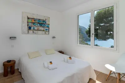 a white bedroom with a white bed and a window at Appartement Mera Cosy apartment with incredible sea view in Èze