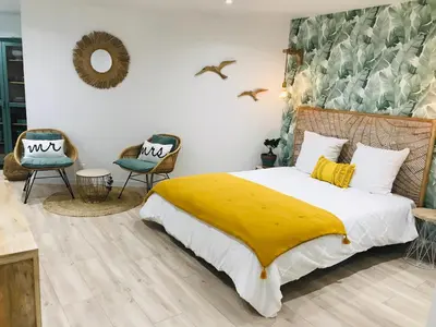 a bedroom with a bed with a yellow blanket and two chairs at Cocon douillet face à la mer de Cagnes sur mer in Cagnes-sur-Mer