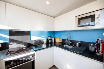 a kitchen with white cabinets and a black counter top at La Terrasse du Port AP4212 in Nice