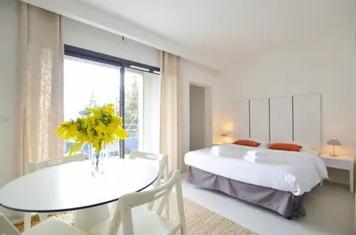 a bedroom with two beds and a table with yellow flowers at La Perle d'Eze - Aparthotel in Èze