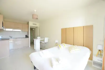 a white room with a white bed and a kitchen at La Perle d'Eze - Aparthotel in Èze